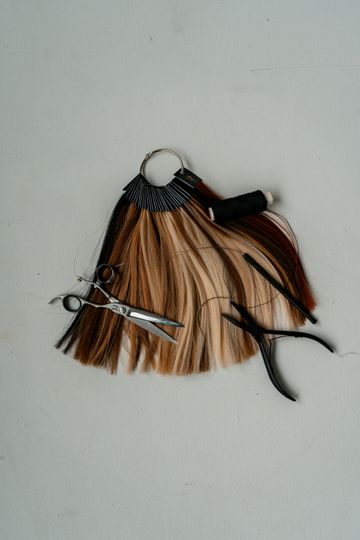 Colour swatches of hair in blonde, brown and copper shades next to a pair of scissors