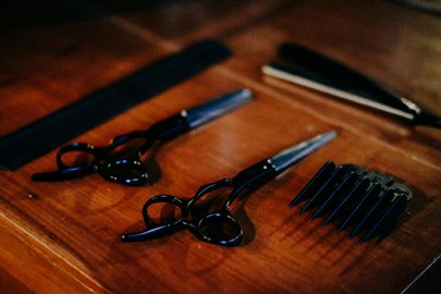 Two pairs of black scissors and a clipper guard on a wooden counter